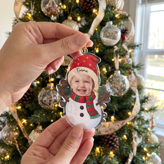 Hand holding the photo face snowman ornament by a Christmas tree