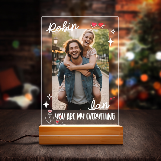 Glowing acrylic couple photo night light on a wooden base with names Robin and Ian and You Are My Everything against Christmas lights
