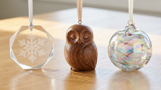 Three keepsake ornaments side by side in acrylic, wood and glass on a bright table