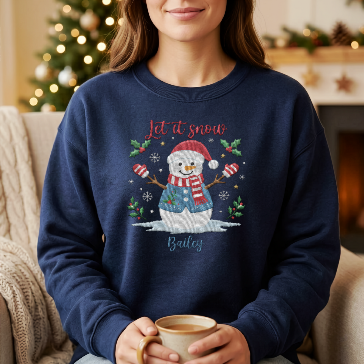 Woman holding a mug wearing the navy Let It Snow embroidered snowman sweatshirt
