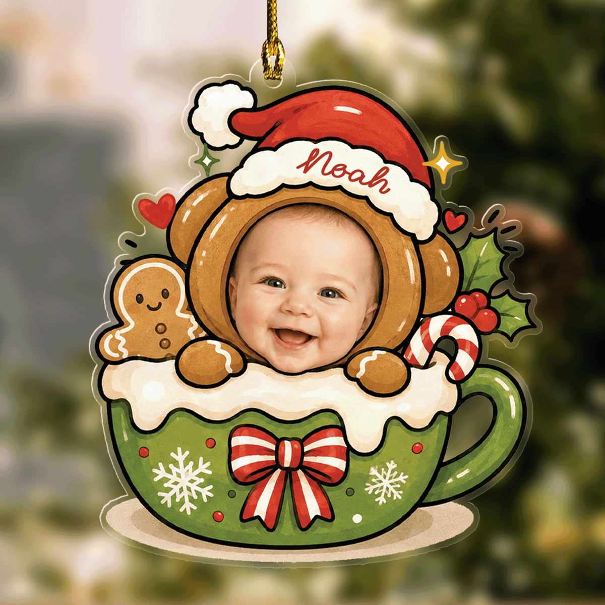 Acrylic ornament of a baby face in a gingerbread bear hood and Santa hat with custom name, peeking from a cocoa mug
