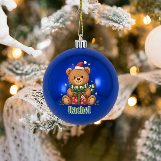 Blue ball ornament with a Christmas teddy bear in a Santa hat holding a gift and custom name