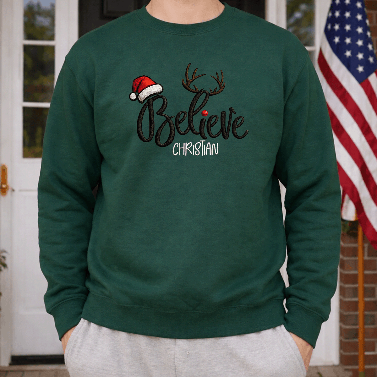 Man wearing a forest green Believe antlers name sweatshirt beside an American flag