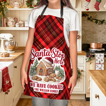 Woman wearing a red plaid Santa Stop Here We Have Cookies apron with gingerbread house and family name