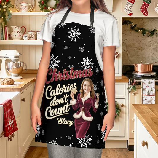 Woman wearing a black snowflake Christmas Calories Don't Count apron with custom photo face in a Santa dress and name