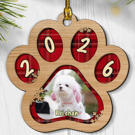 Paw shaped wood ornament with red plaid toe pads showing 2026 and a white dog photo with a custom pet name