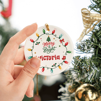 Hand holding the round Merry and Bright personalized ceramic ornament