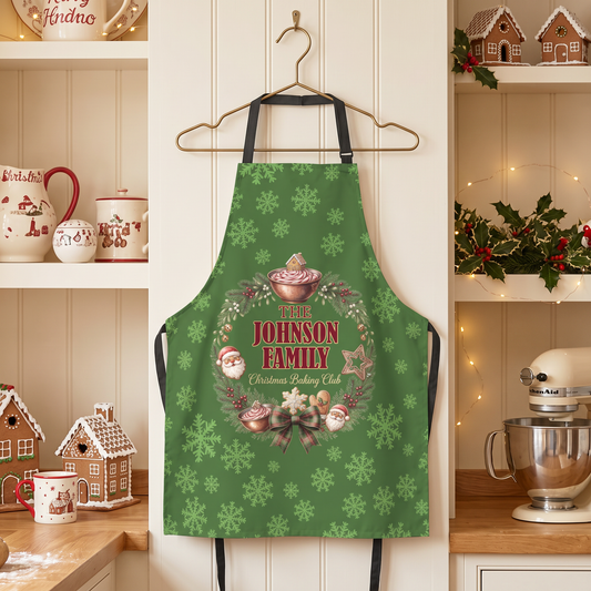 Green snowflake pattern apron with Christmas Baking Club wreath and custom family name on a hanger