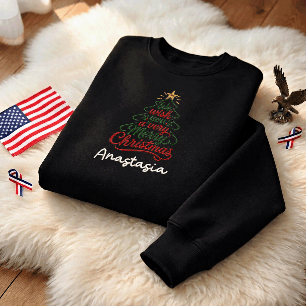 Black We Wish You a Merry Christmas sweatshirt on a fur rug with a small flag and eagle