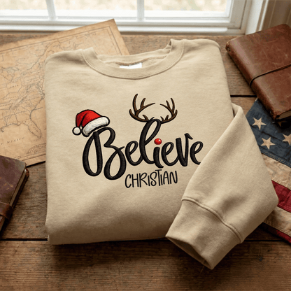 Sand Believe Santa hat antlers name sweatshirt folded on a map