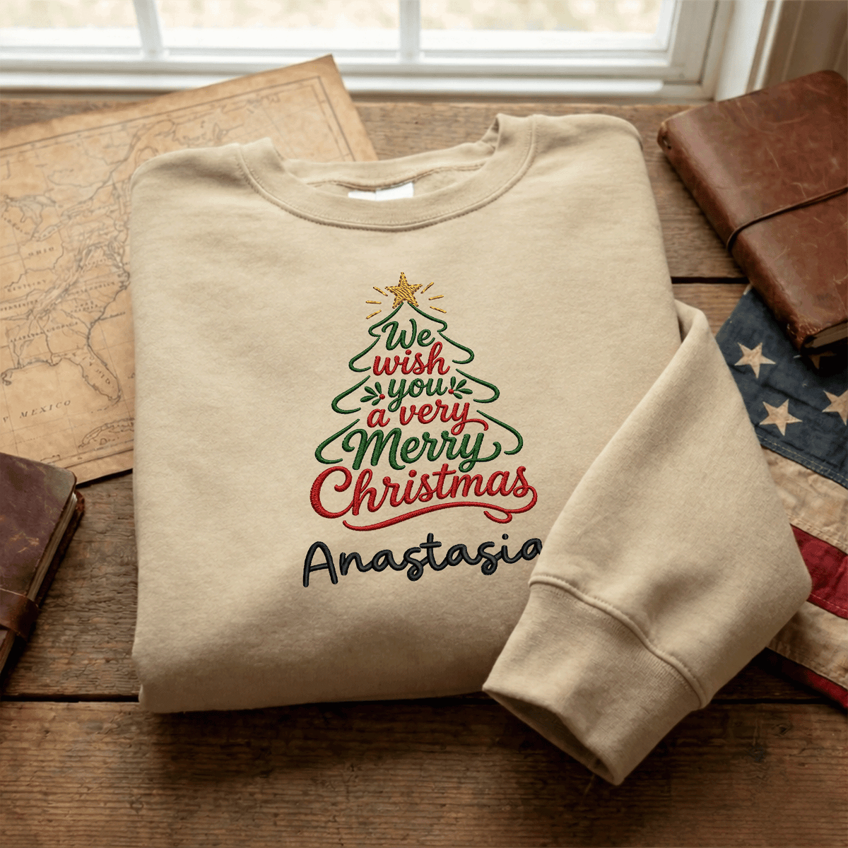 Sand Merry Christmas script tree name sweatshirt folded on a map