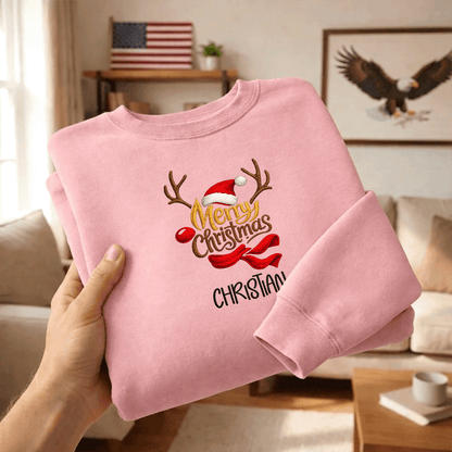 Hands holding a folded pink Merry Christmas reindeer embroidered sweatshirt
