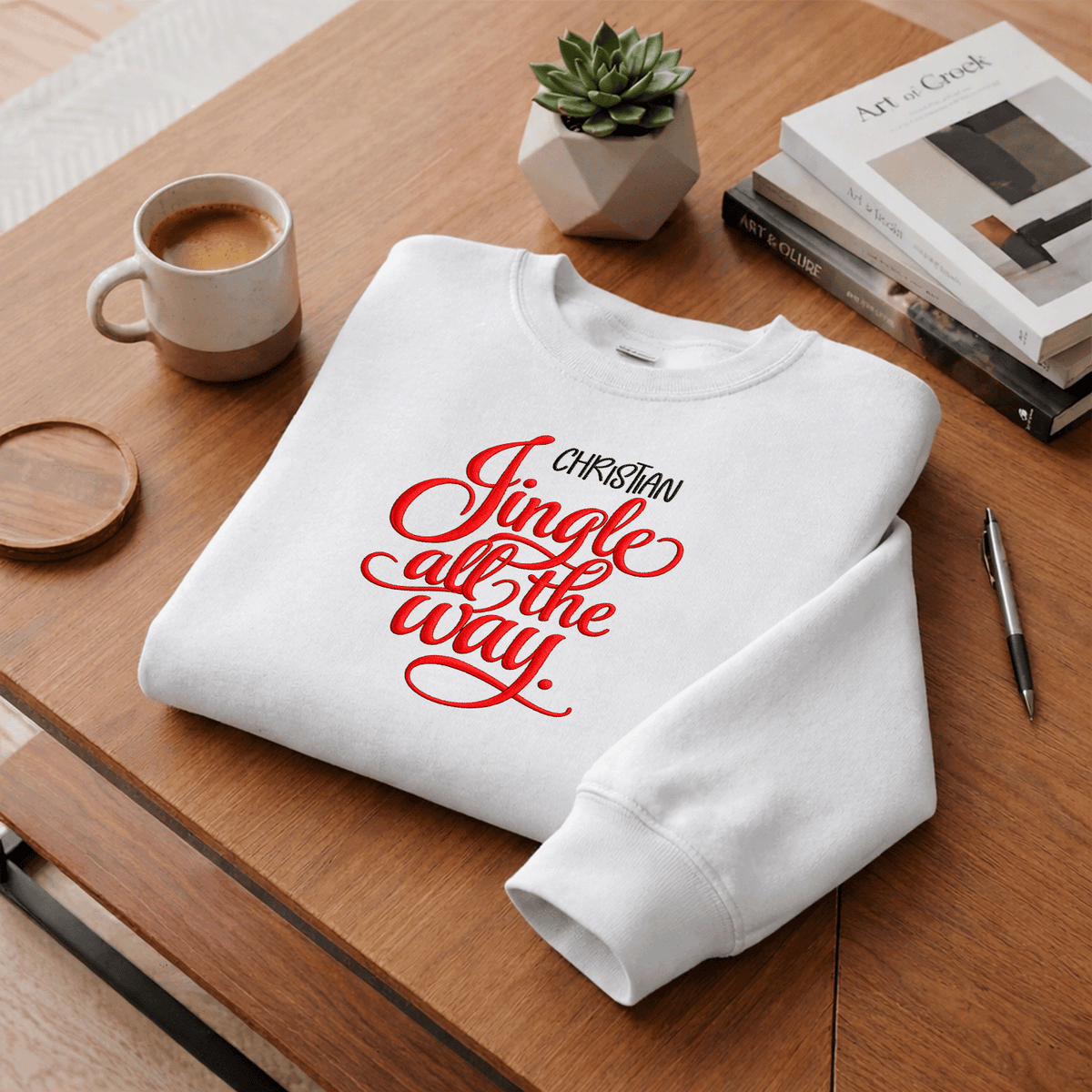 White Jingle All the Way custom name sweatshirt folded on a desk with coffee