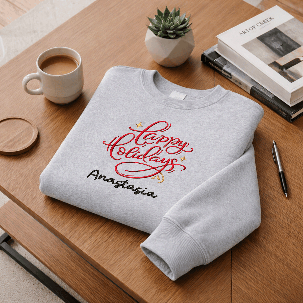Heather grey red Happy Holidays sweatshirt folded on a desk