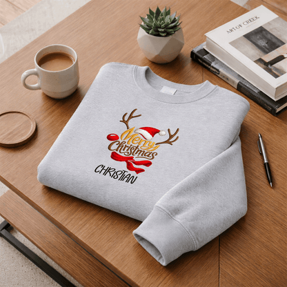 Heather grey Merry Christmas reindeer antlers sweatshirt folded on a desk