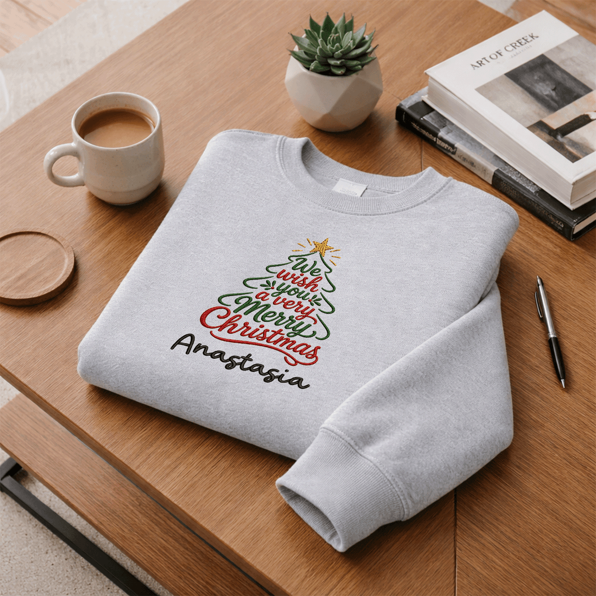 Heather grey We Wish You a Merry Christmas sweatshirt folded on a desk