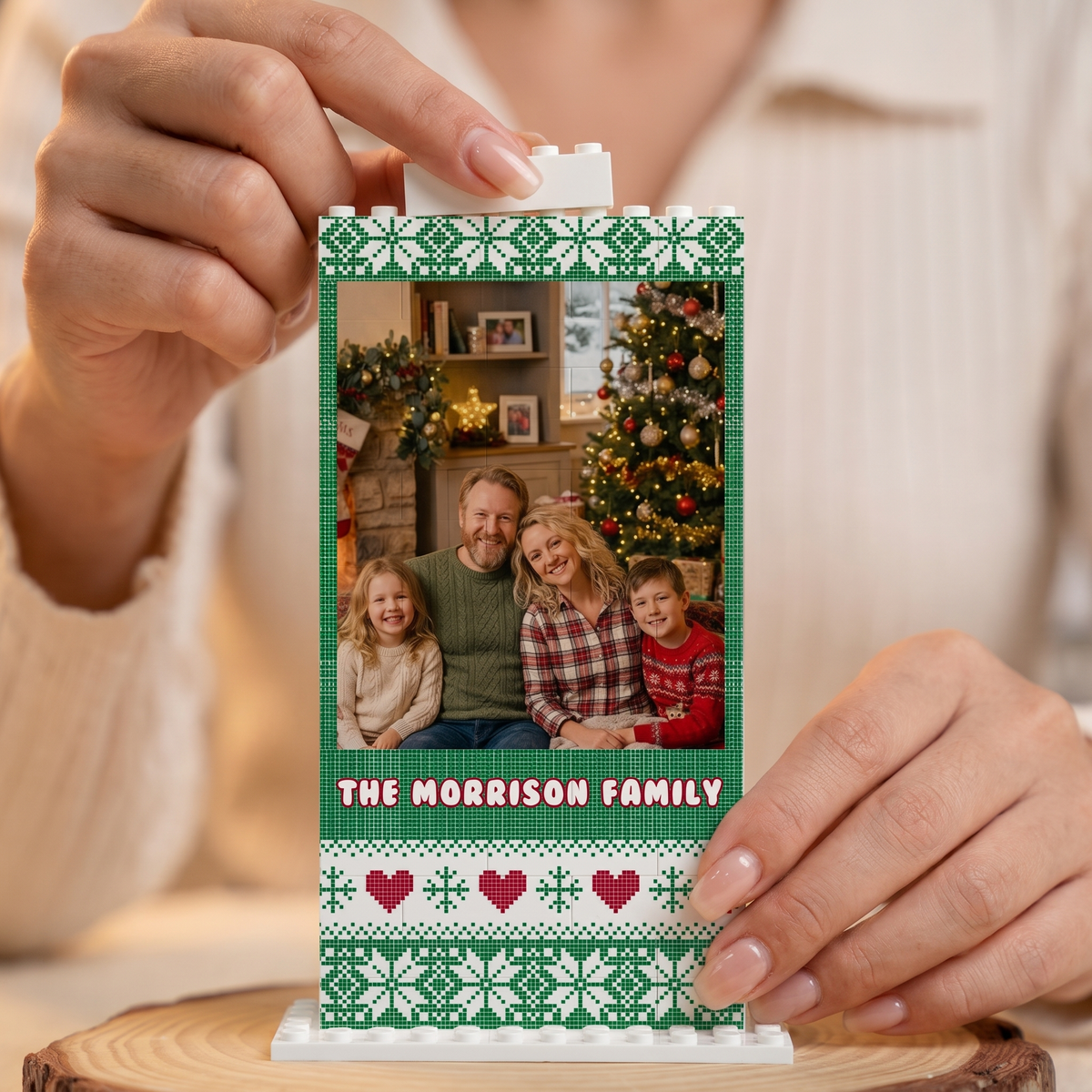 Hand placing a brick on the Fair Isle Sweater Knit family photo building block frame