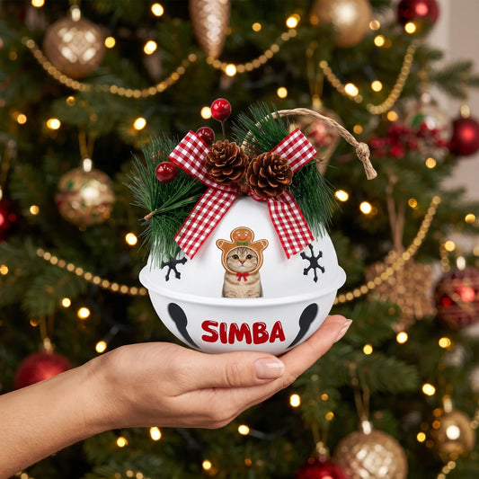 Personalized gingerbread pet jingle bell ornament held in hand by a Christmas tree