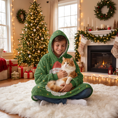 Child wrapped in the Santa Face Golden Stars hooded blanket holding a cat by the Christmas tree