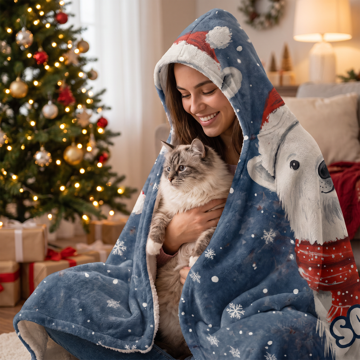 Smiling woman snuggled in the Polar Bear Santa Hat Snowfall hooded blanket with her cat by the Christmas tree