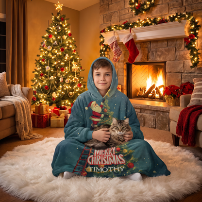 Child wrapped in the Santa Ladder Christmas Tree Star hooded blanket holding a cat by the Christmas tree