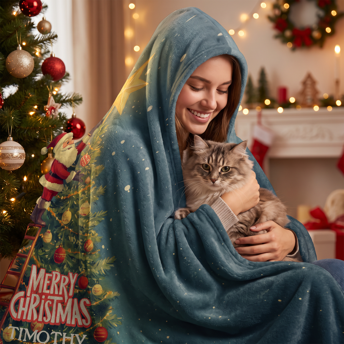 Smiling woman snuggled in the Santa Ladder Christmas Tree Star hooded blanket with her cat by the Christmas tree