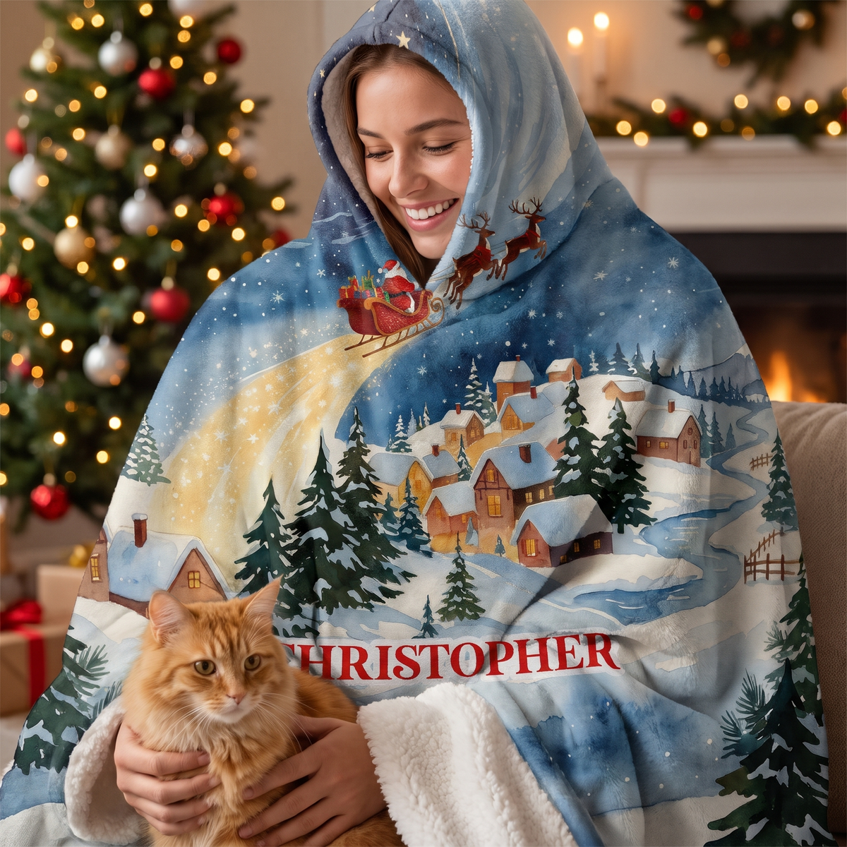 Smiling woman snuggled in the Santa Sleigh Snowy Village hooded blanket with her cat by the Christmas tree