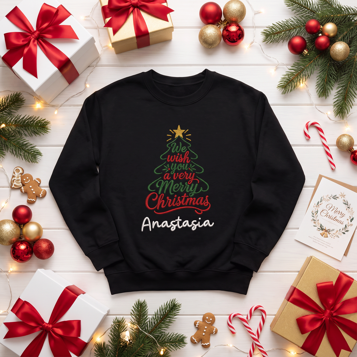 Black sweatshirt embroidered with a Christmas tree formed by We Wish You a Very Merry Christmas script, a gold star and custom name