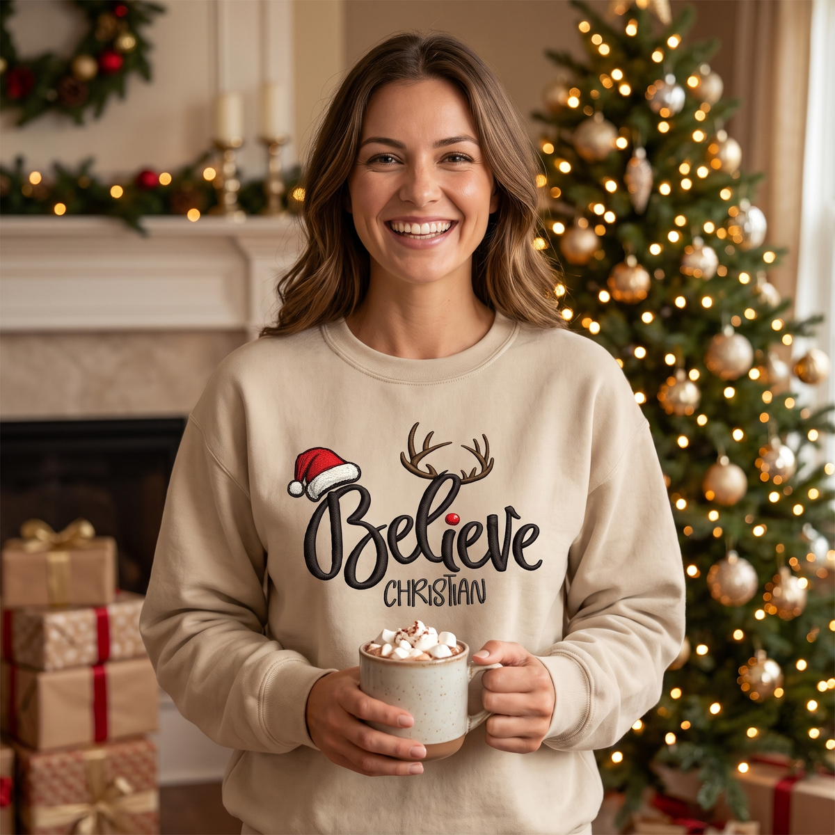 Smiling woman in a sand Believe antlers sweatshirt holding cocoa by the tree