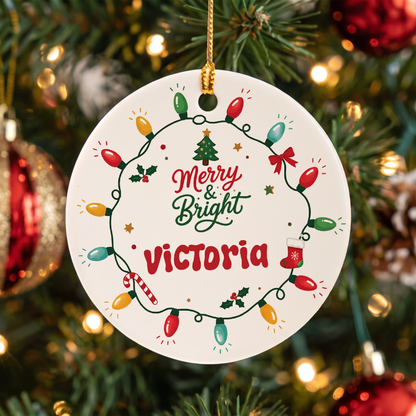 Round white ceramic ornament with a colorful Christmas lights wreath, Merry and Bright and a custom name in red