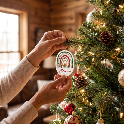 Hands hanging the personalized Christmas rainbow ornament on a tree