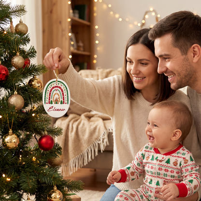Parents and baby hanging the custom name Christmas rainbow ornament on the tree