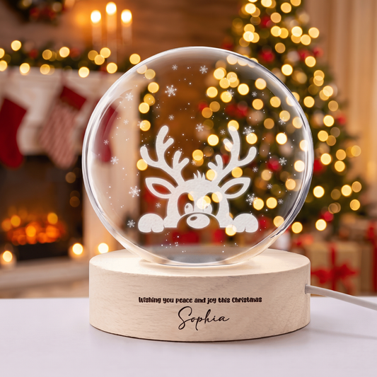 Crystal ball engraved with a peeking reindeer and snowflakes on a wooden base with holiday message and custom name