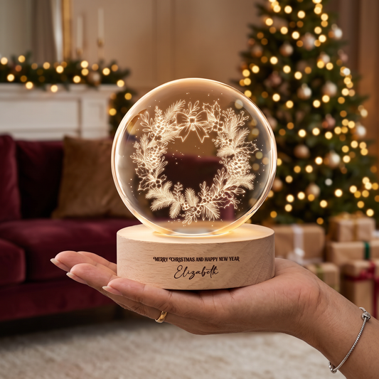 Hand holding the glowing pinecone holly wreath crystal ball with custom name base in a festive living room