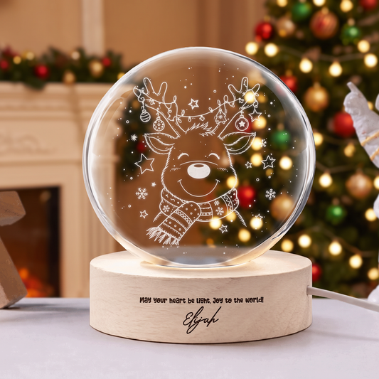 Crystal ball engraved with a smiling reindeer in a knit scarf and ornament antlers on a wooden LED base with custom name
