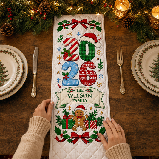 Hands placing a white quilt runner with patterned 2026 numbers in a Santa hat, custom family name banner and gingerbread man with gifts
