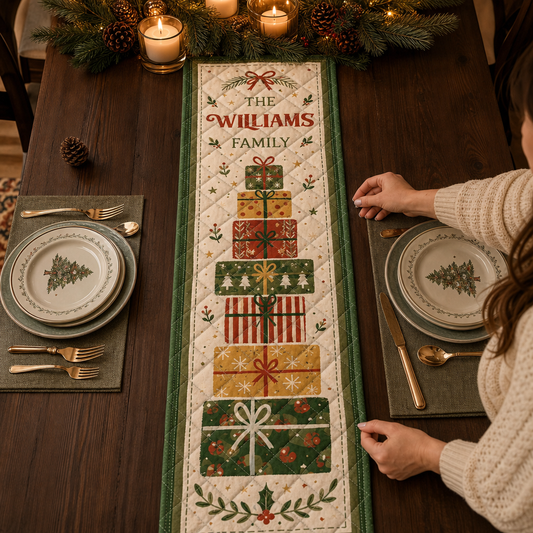 Hands placing a cream quilt runner with a tall stack of red, gold and green presents and custom family name