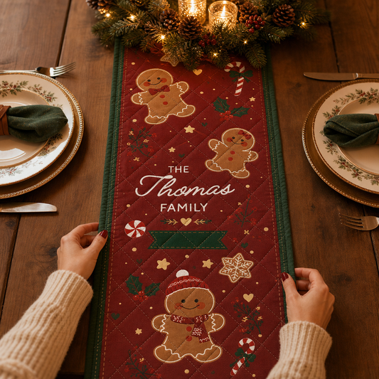 Hands placing a red quilt runner with smiling gingerbread cookies, candy canes, custom family name and green border