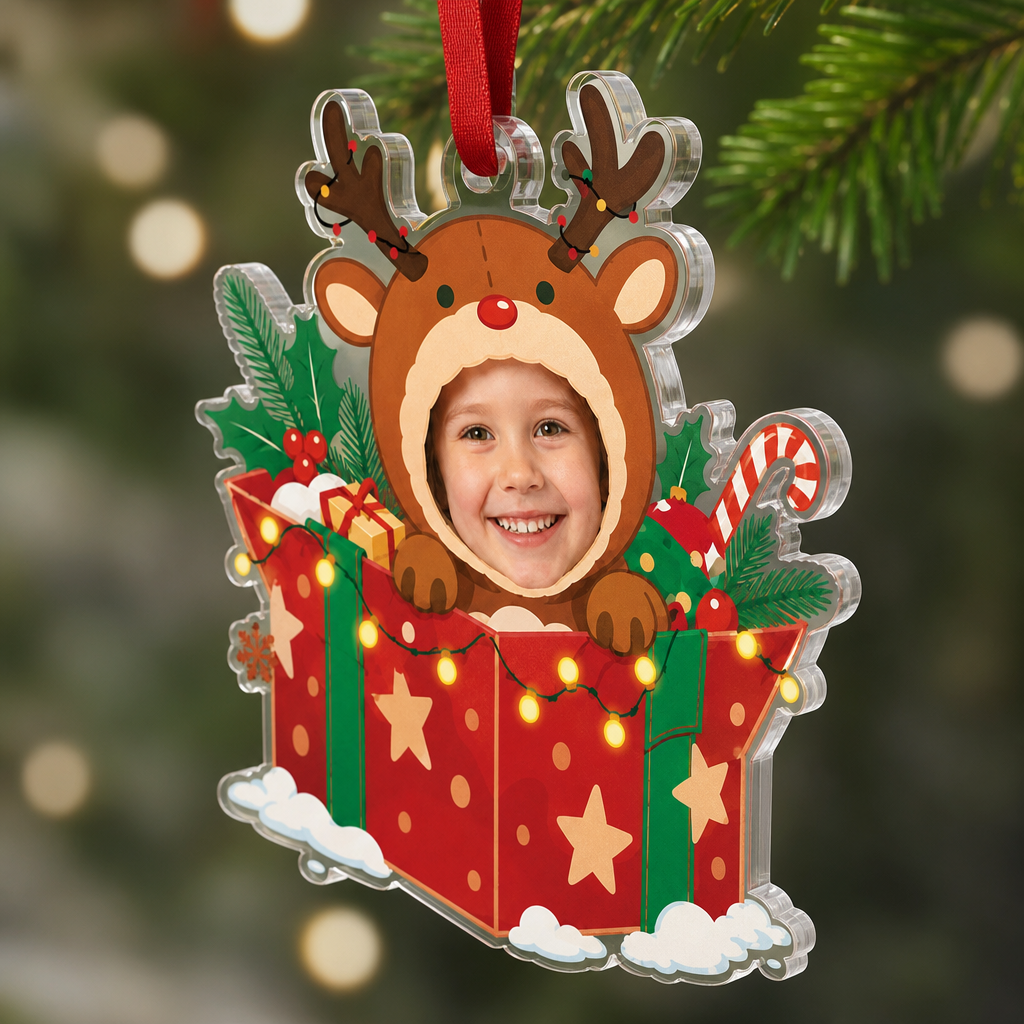 Side view of the clear acrylic reindeer in gift box face ornament on a red ribbon