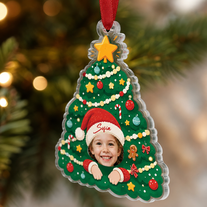Side view of the clear acrylic kid face Christmas tree ornament on a red ribbon