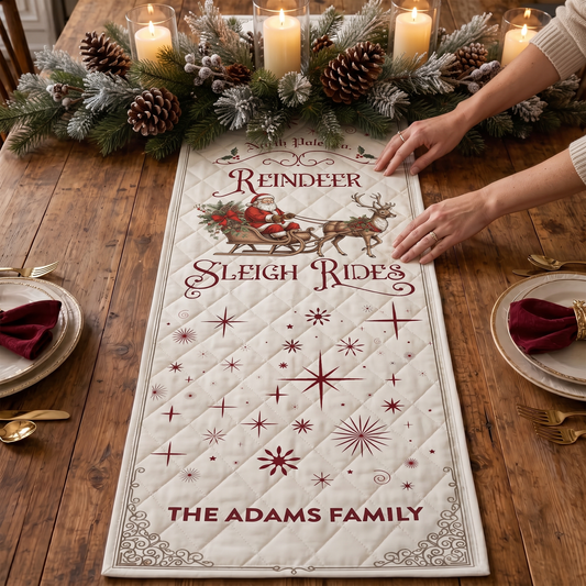 Hands placing a cream North Pole Co. Reindeer Sleigh Rides quilt runner with vintage Santa sleigh and custom family name