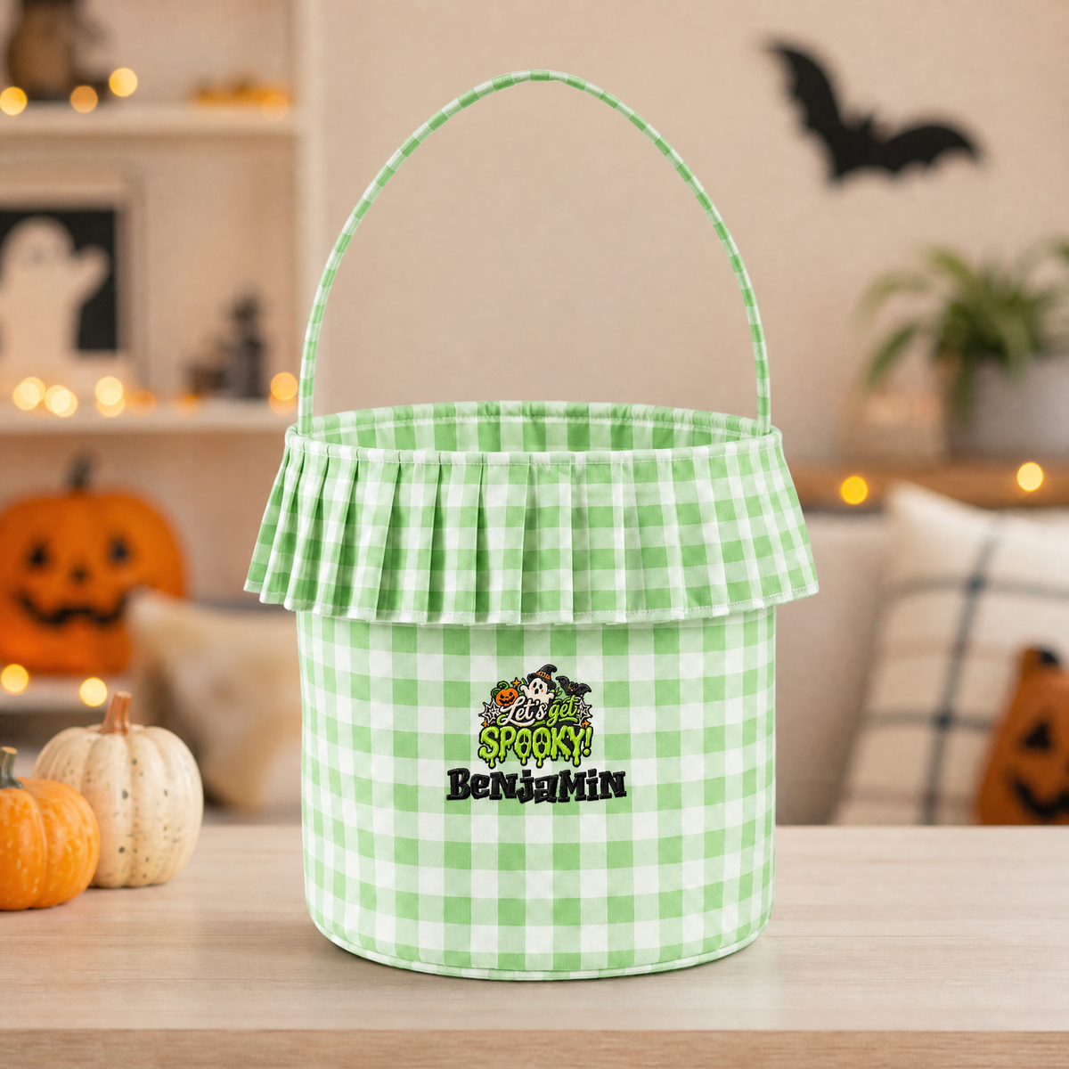 Green gingham ruffle Halloween basket embroidered with Let's Get Spooky and a custom name on a table with pumpkins