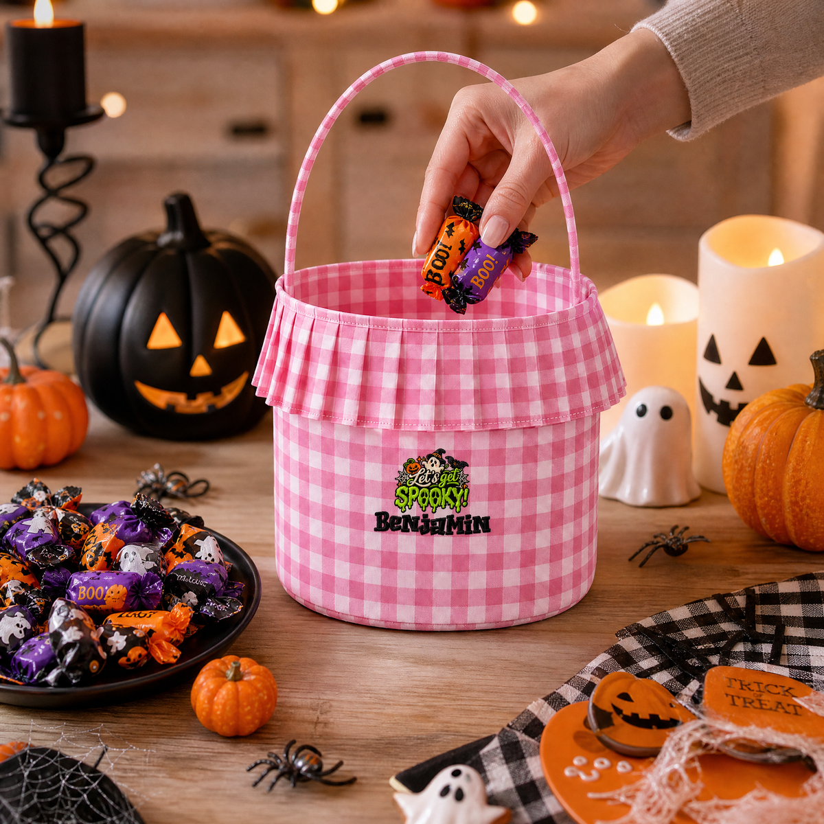 Hand dropping candy into a pink gingham ruffle basket embroidered with Let's Get Spooky and a custom name