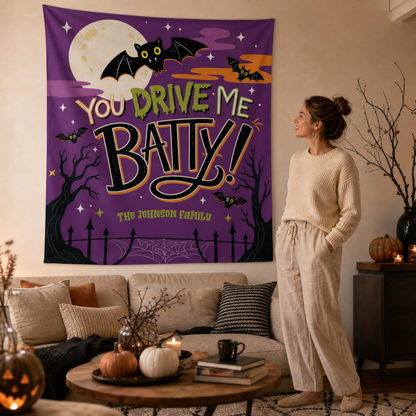 Woman in a cream sweater admiring a purple You Drive Me Batty Halloween wall tapestry in her living room