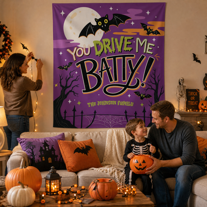 Family decorating for Halloween under a personalized You Drive Me Batty tapestry with a child in a skeleton costume