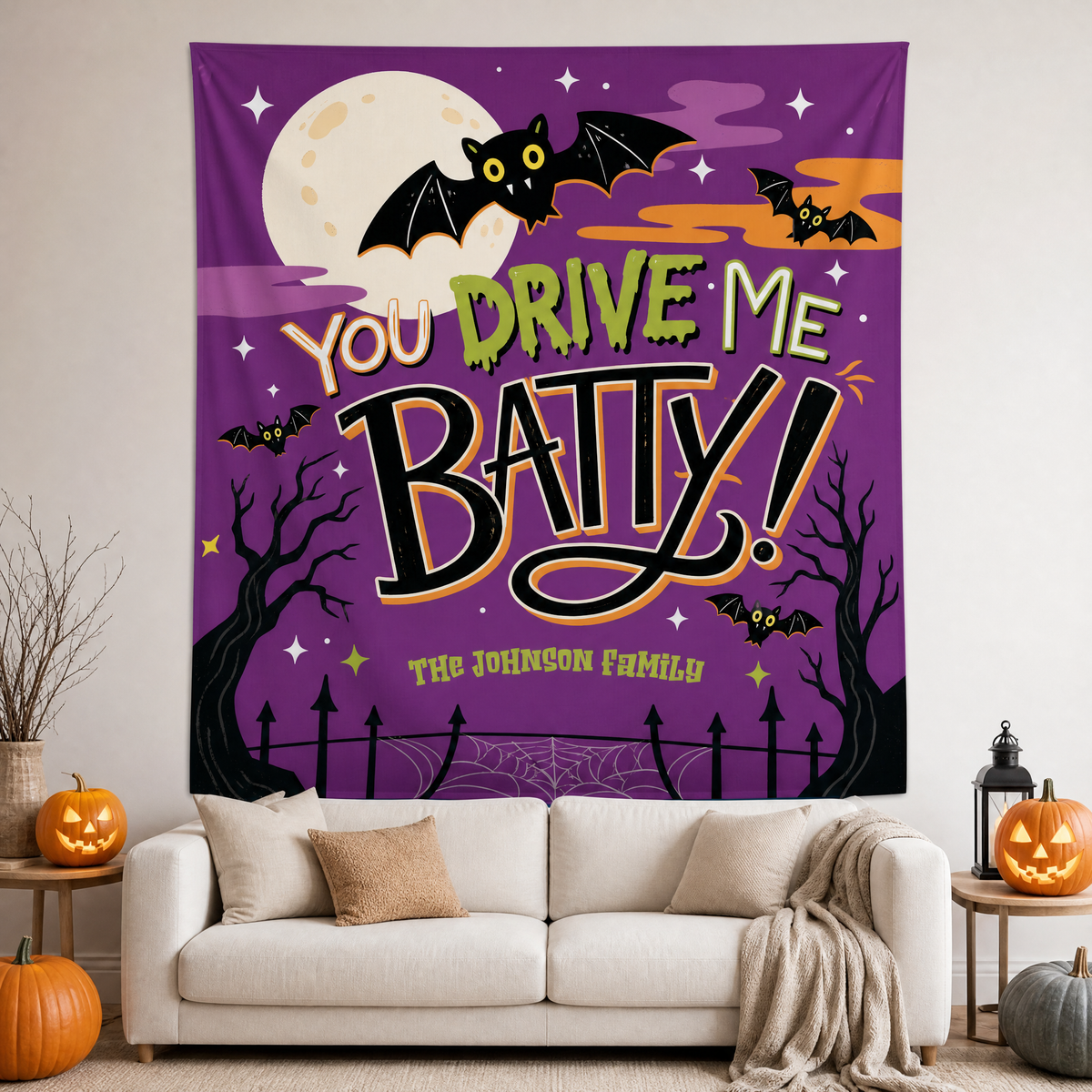 Purple Halloween tapestry reading You Drive Me Batty with bats, full moon and custom family name above a white sofa