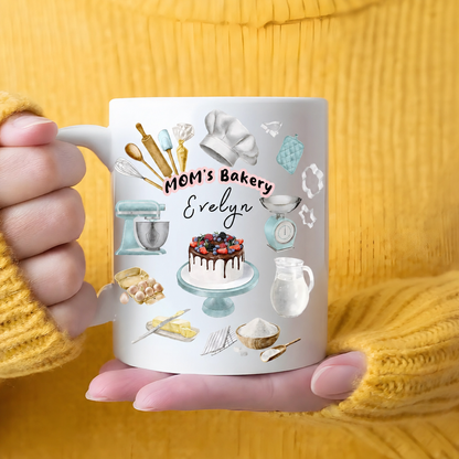 Hands in a yellow sweater cradling a MOM's Bakery custom name mug with berry cake and mint mixer design