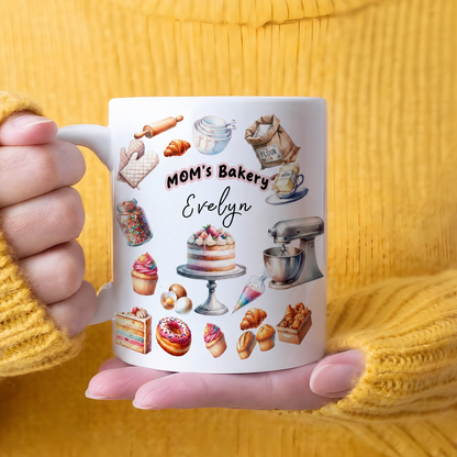 Woman in a mustard sweater holding a MOM's Bakery custom name mug printed with cakes, donuts and pastries