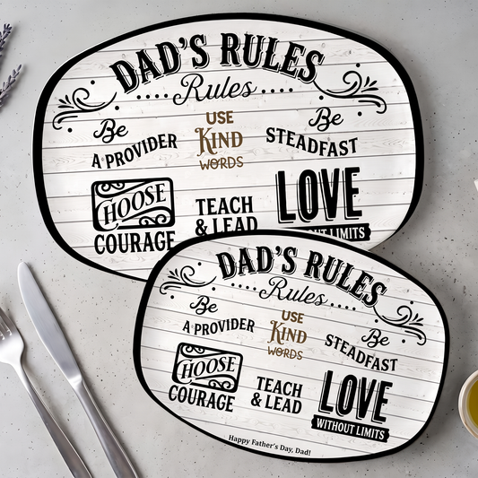 Two sizes of the Dad's Rules oval serving platter overlapping on grey stone beside a knife and fork
