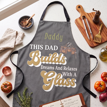 Charcoal grey apron with custom name Daddy, tool belt art and retro text This Dad Builds Dreams And Relaxes With A Glass
